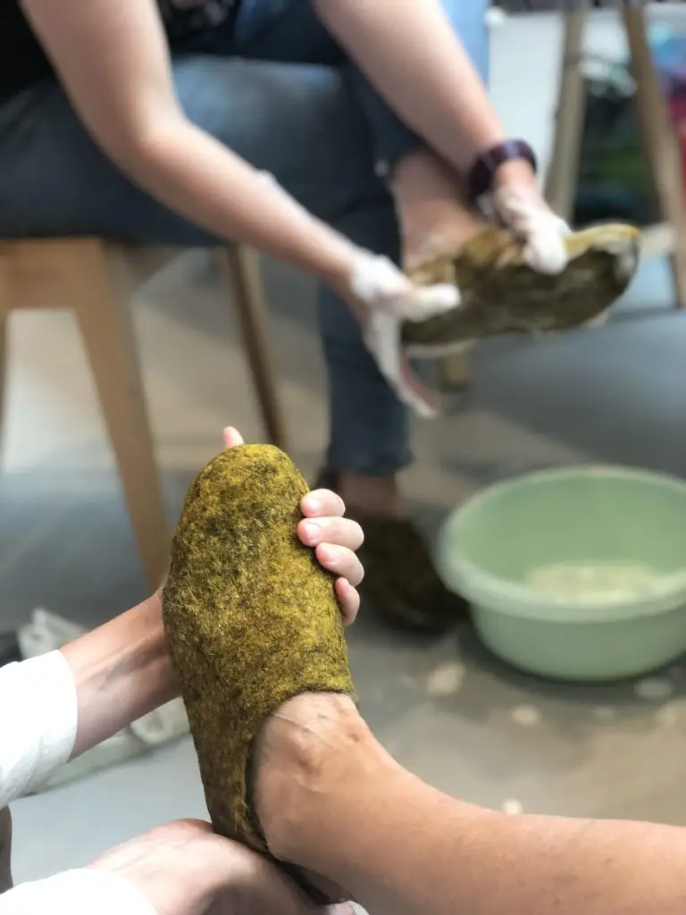 Deelnemer vormt natte wol tot een vilten slof tijdens een workshop in het Schoenenlab.