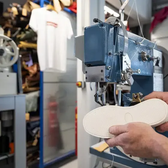 Schoenzool wordt geperst in een industriële machine tijdens productieproces.