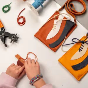 Werktafel met leren telefoontasjes, gereedschap en materialen tijdens een creatieve workshop in het Schoenenkwartier.