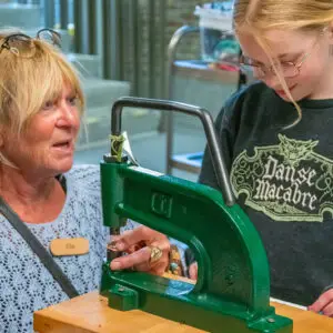 Child is explained and guided while making a bracelet, here she learns to attach a clasp to the bracelet during a children's party at the Shoe Quarter