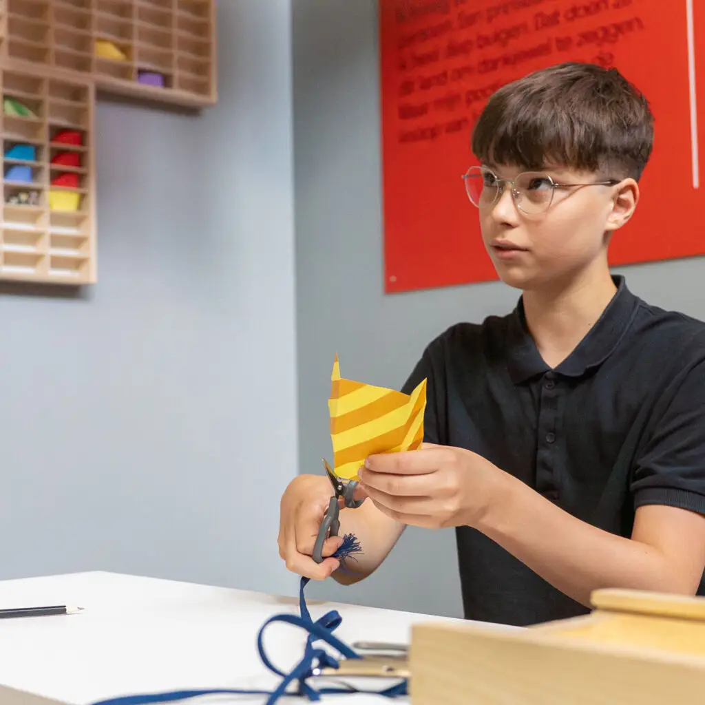 Visitor playfully learns to fold a shoe using origami technique during the Grand Hotel during summer vacation at the Shoe Quarter