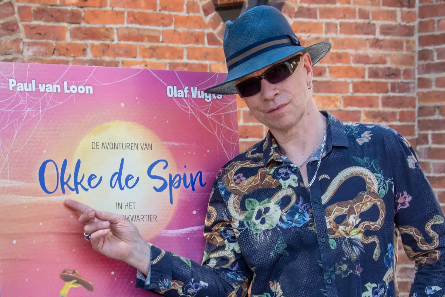Paul van Loon next to the book cover of the adventures of Okke the Spider in the Shoe Quarter during the book launch.