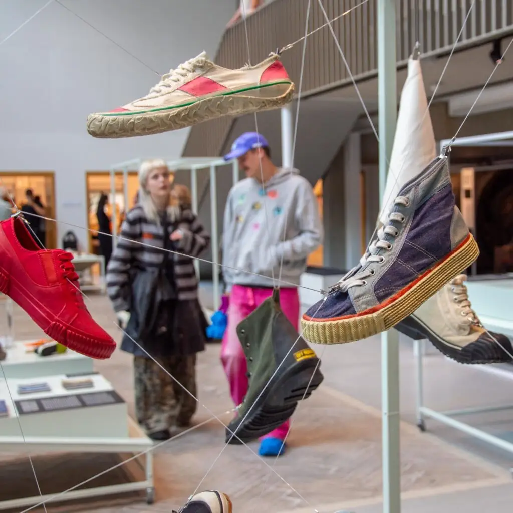 Sneaker Evolution exhibition in the Shoe Quarter with floating sneakers in different colors, with visitors viewing the collection.