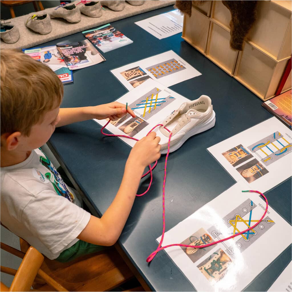 Kind leert veters strikken met creatieve strikmethodes via instructiekaarten in het kenniscentrum van het Schoenenkwartier