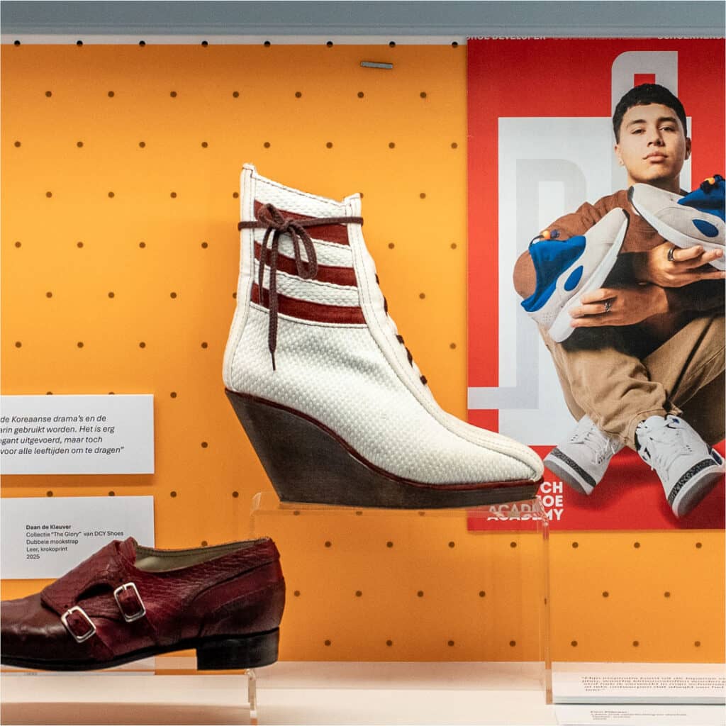 Spotlightkast opstelling met een witte laars met rode details en sleehak tegen een gele achtergrond, onderdeel van de studentenpresentatie Shoe Developer in het Schoenenkwartier.