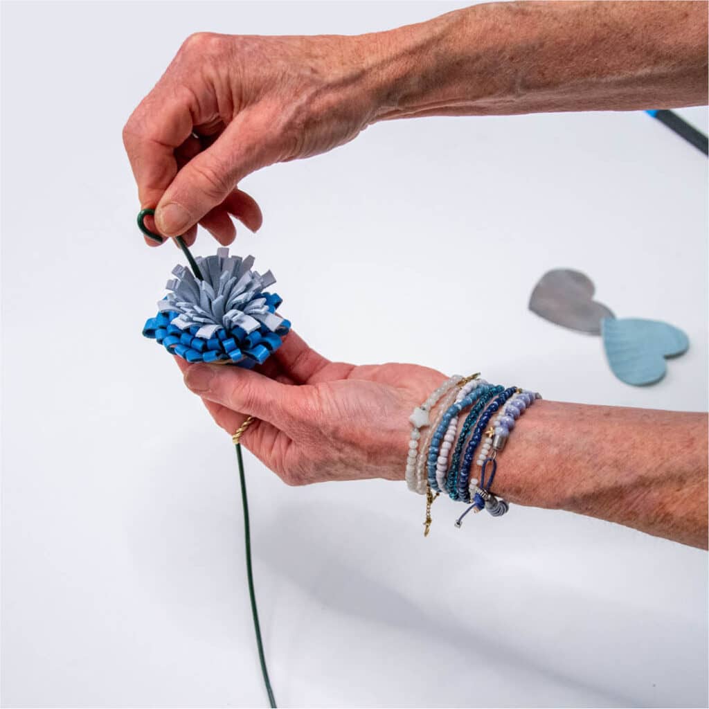 Handen werken met blauw en zilver leer en gereedschap tijdens een leren bloemen maak workshop in het Schoenenkwartier.