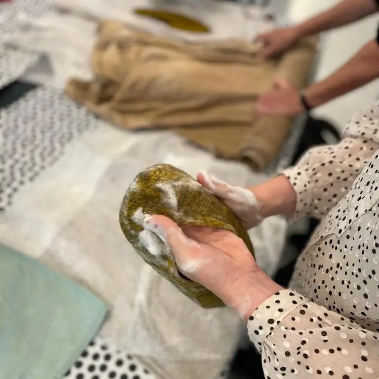 Vilten slof in wording wordt gekneed en gevormd op de werktafel tijdens de workshop.