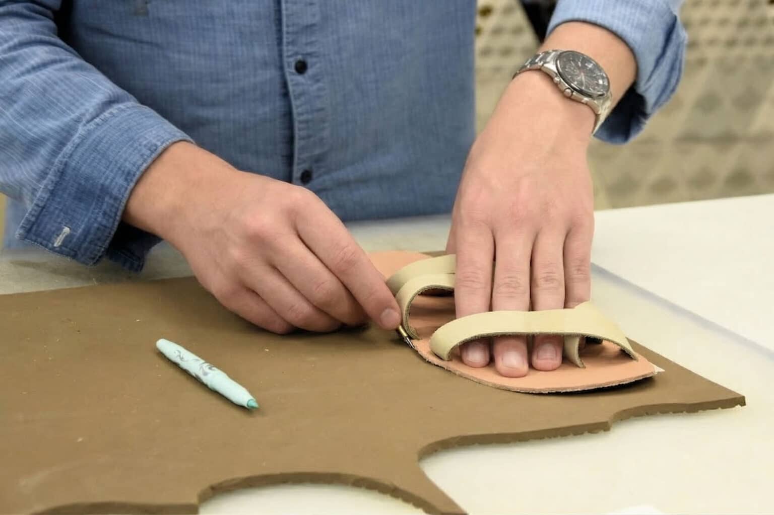 Workshop deelnemer die zijn zool uitsnijd voor een zelfgemaakte Sandaal in het Schoenenlab