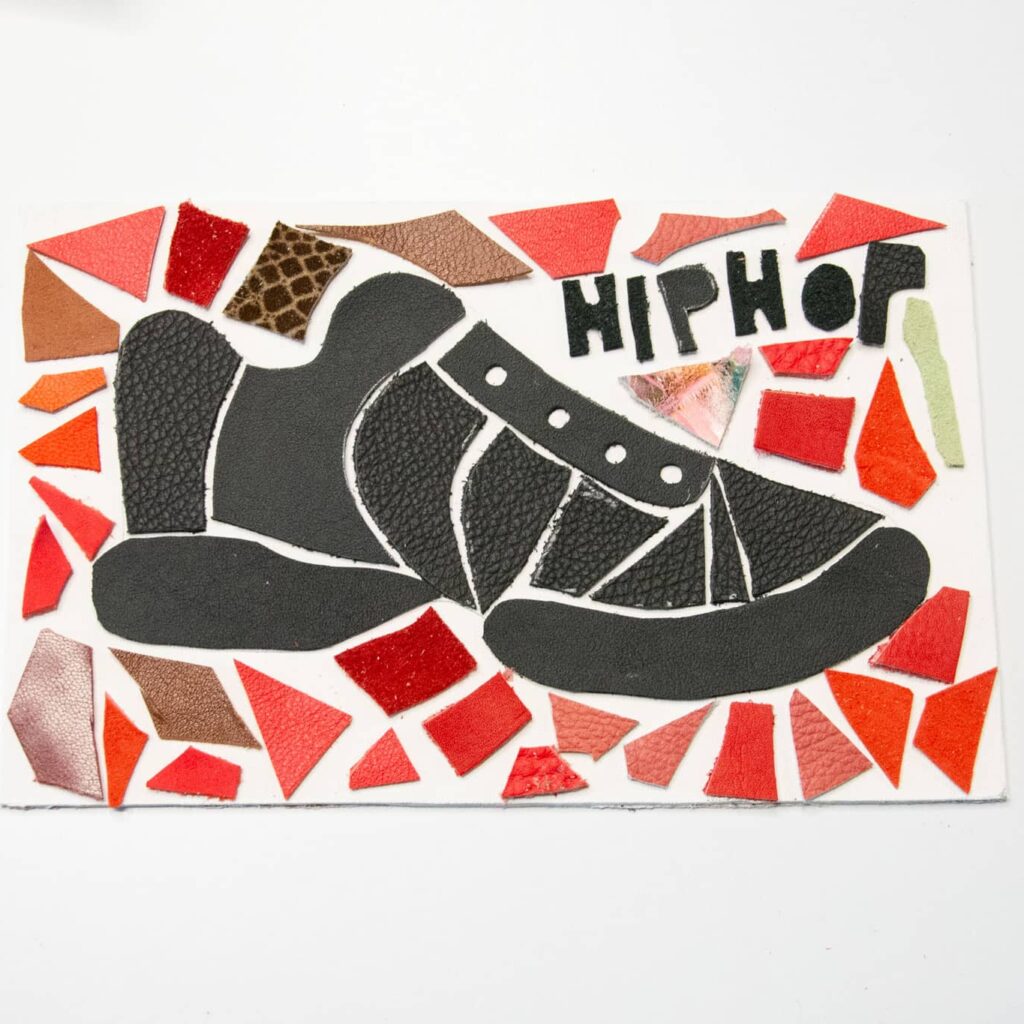 Afgewerkt mozaïek van een sneaker opgebouwd uit rood, oranje en zwart leer, met het woord HIPHOP verwerkt in het ontwerp.