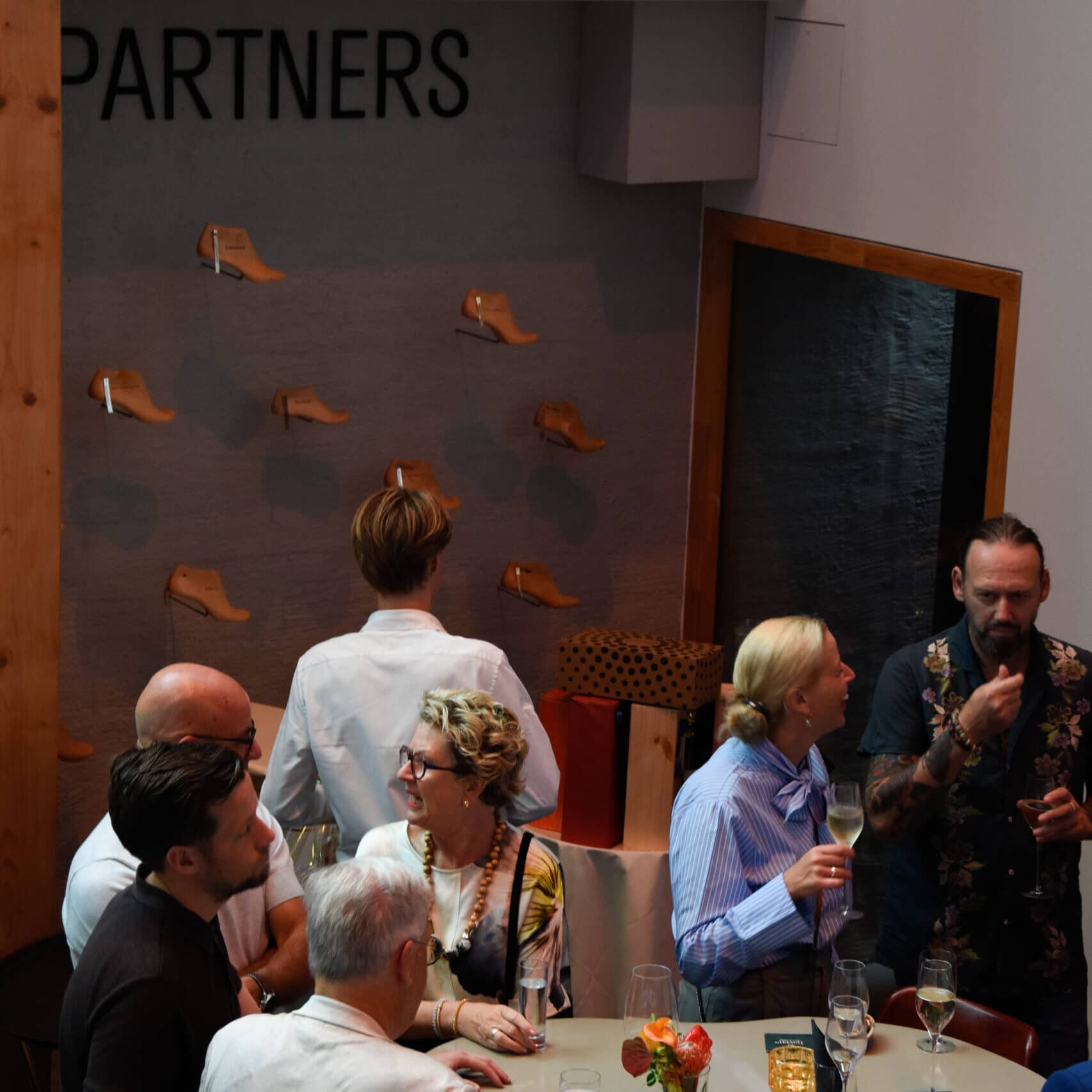Bezoekers in gesprek tijdens een zakelijk evenement bij het Schoenenkwartier in Waalwijk, met het opschrift 'Partners' zichtbaar op de achtergrond.